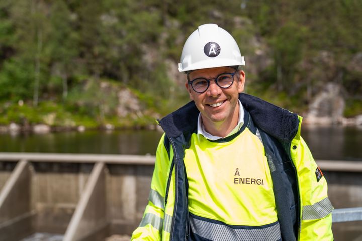 Kraftverk, dam, vann, mann med vernetøy og hjelm. Foto.