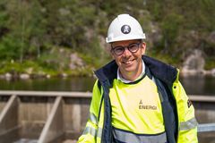 Kraftverk, dam, vann, mann med vernetøy og hjelm. Foto.