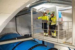 To mennesker iført verneklær inne i en kraftstasjon. Foto.