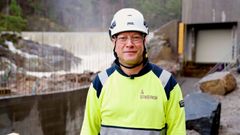 Mann iført verneutstyr, kraftverksdam, vann. Foto.