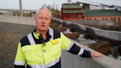 Mann i arbeidsklær ved laksetrapp. Foto.