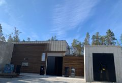 Kraftverksbygg, himmel, skog. Foto.