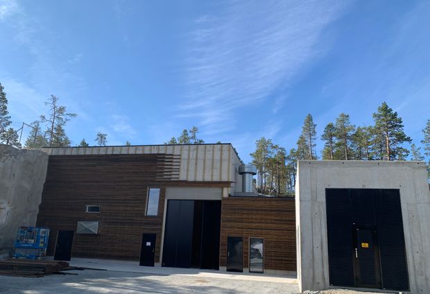 Kraftverksbygg, himmel, skog. Foto.