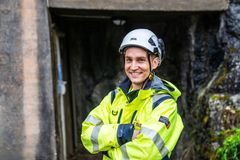 Mann, vernetøy, hjelm, murvegg. Foto.