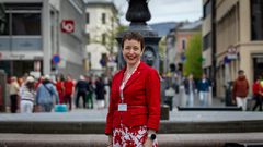 Ingerid Marie Utvik i rød dressjakke foran fontenen på Youngstorget, LO-bygget såvidt synlig i bakgrunnen.
