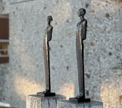 To bronseskulpturer står på hver sin granittsokkel.