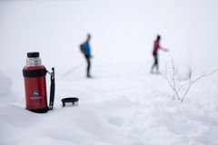 Termos i snøen og to mennesker på skitur i marka. Foto: Per Anders Bjørklund / Kartverket