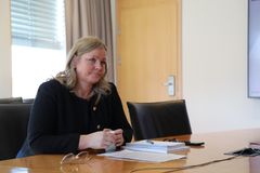 Kjersti Stenseng sitter ved et bord i et møterom. På bordet foran henne ligger en rapport.