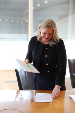 Kvinne i et møterom holder en rapport.