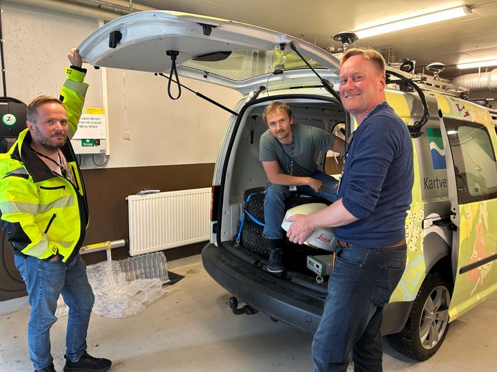 Tre personer fra Kartverkets geodesidivisjon pakker utstyr som skal brukes på Jammertest, inn i en bil.