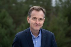 En mann i dress står foran en uskarp grønn bakgrunn.