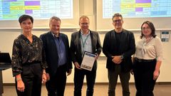 Gruppebilde av fem mennesker hvor den ene holder et innrammet godkjenningsbrev for masterprogrammet i eiendom, tildelt NMBU.