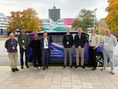 Gruppebilde av åtte personer foran en lilla bil i Stockholm.