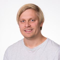 Mann med lyst hår og lys t-skjorte smiler.