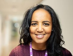 Dame i lilla genser smiler til kamera.