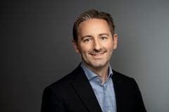 Portrett av en mann i dressjakke og lys blå skjorte.