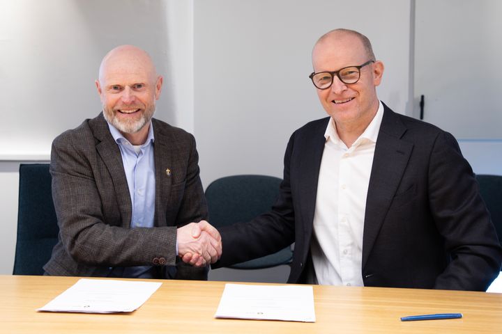 To%20menn%20i%20dress%20h%E5ndhilser%20over%20et%20bord%20med%20dokumenter.