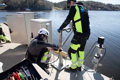 To personer fra Kartverket installerer en vannstandsmåler på en kai i Eydehavn, Arendal.