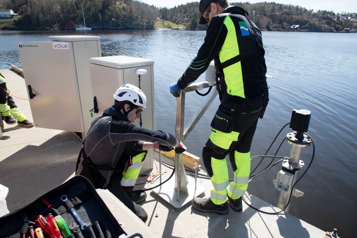 To personer fra Kartverket installerer en vannstandsmåler på en kai i Eydehavn, Arendal.