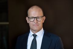 En mann i dress står foran en mørk bakgrunn.