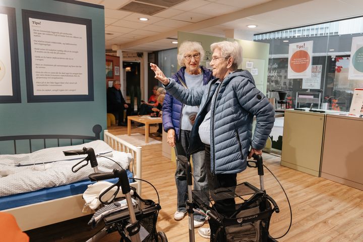 To eldre kvinner med rullator besøker utstillingen «Den trygge boligen» og ser på fallforebyggende tiltak.