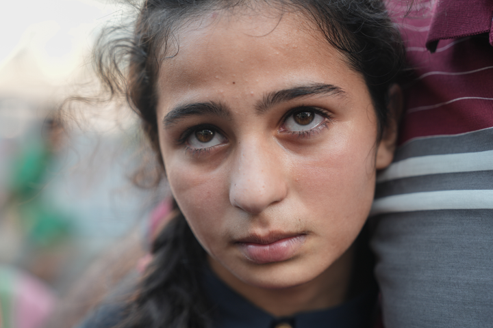 En ung jente står i kø for å få drikkevann ved en FN-skole i Gaza.