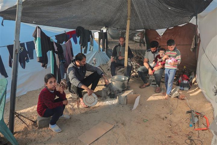 En palestinsk familie lager mat over et mål i en provisorisk flyktningleir i Rafah by nær grensen til Egypt.