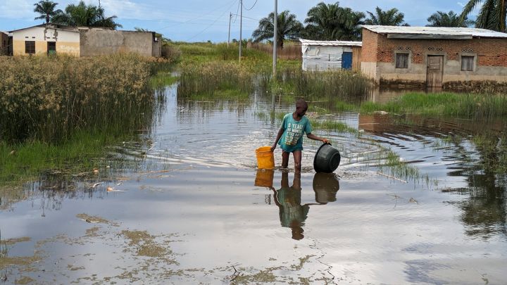 En gutt som går gjennom flomvannet i landsbyen Gatumba i Burundi.