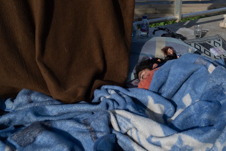 En jente sover på et teppe med dukken sin langs strandveien i Beirut, Libanon den 13. mars 2026.