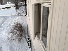 Halvåpent vindu på hus med snø utenfor
