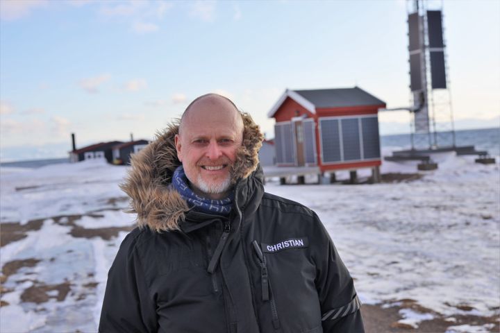 ISKALDE FORHOLD: Christian Skottun, her foran en av basestasjonene på Svalbard. Allerede i 2019 tok Telenor Svalbard solenergi i bruk ved flere av sine basestasjoner for å redusere bruken av fossil energi. Foto: Stian Kristoffer Sande, Telenor.