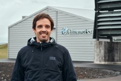 En smilende mann i jakke står foran en bygning med Climeworks-logoen.