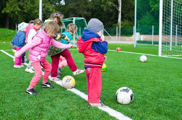 Barn på en fotballbane som leker med ball.