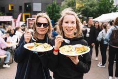 To kvinner ser smilende i kamera med hver sin vietnamesiske pannekake på en tallerken.