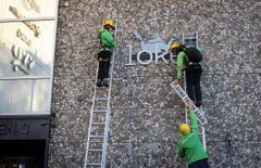 NY LOGO: Aktivister fra Greenpeace henger opp en ny logo på veggen til Loke Marine Minerals i Stavanger. Logoen spiller på at selskapet har valgt navnet Loke, etter den ondskapsfulle luringen fra norrøn mytelogi.