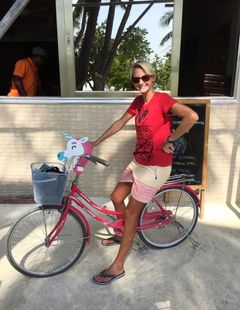 Kvinne sitter på sykkel med enhjørning på styret.