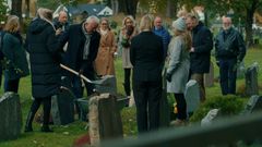 Jonas' far kaster jord på kisten i begravelsen.