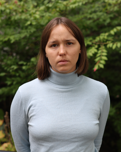 Leder i Spire Thea Birgitte Erfjord står med et alvorlig ansiktsuttrykk foran en grønn bakgrunn