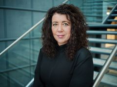 Generalsekretær står foran en moderne trapp i et bygg med metalliske detaljer.