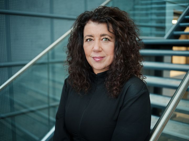 Generalsekretær står foran en moderne trapp i et bygg med metalliske detaljer.