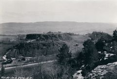 Svart-hvitt bilde av Sverresborg festning sett fra en høyde i 1936. Landskapet er omkranset av bakker og noen spredte trær.