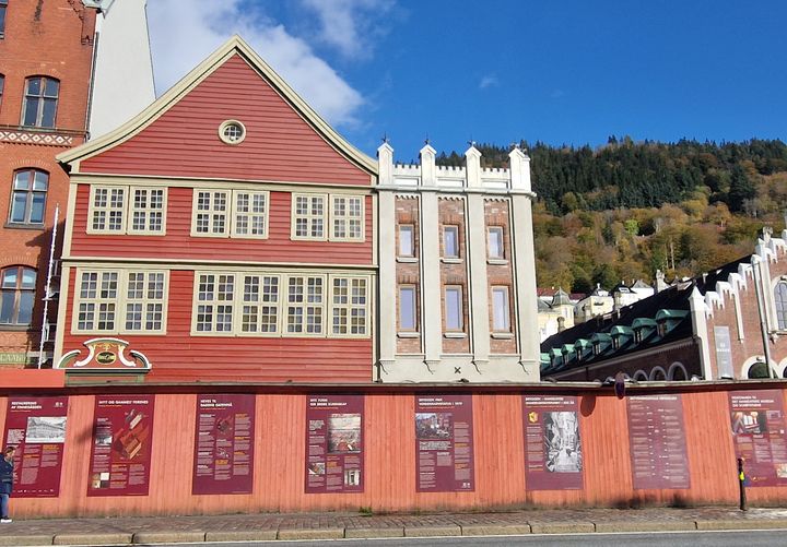 Bildet viser fasaden på Finnegården, Bryggen i Bergen, som består av en rød trebygning (Sjøstuen) og Murtasken. Foran fasaden er et byggegjerde.