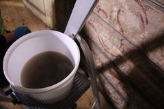 En vaskebøtte med veldig skittent vann står på en gardintrapp. I bakgrunnen ses en tømmervegg med limfargedekor.