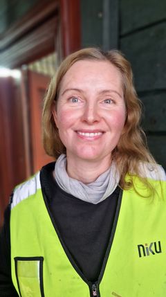 Portrett av Anne Apalnes Ørnhøi, prosjektleder for NIKUs konserveringsarbeider i Finnegården. Hun smiler og er iført en gul vest.