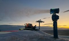 Snøkanon lager kunstsnø ved solnedgang i Hafjell, med en tråkkemaskin i bakgrunnen.