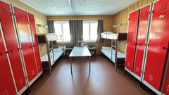 Bilde av et nyrestaurert seksmannsrom på kasernen med køyesenger og røde skap.