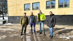 Bildet viser fire personer som står foran den nyrenoverte kasernen Heistad på Skjold.