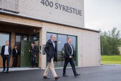 To personer i formelle klær går foran et nybygg merket '400 sykestue'.