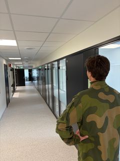 Soldat ser nedover kontorgang i kontorbygg Rena