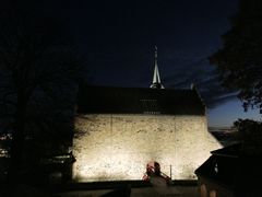 Nattbilde av Akershus slott med opplyste murer og tårn.